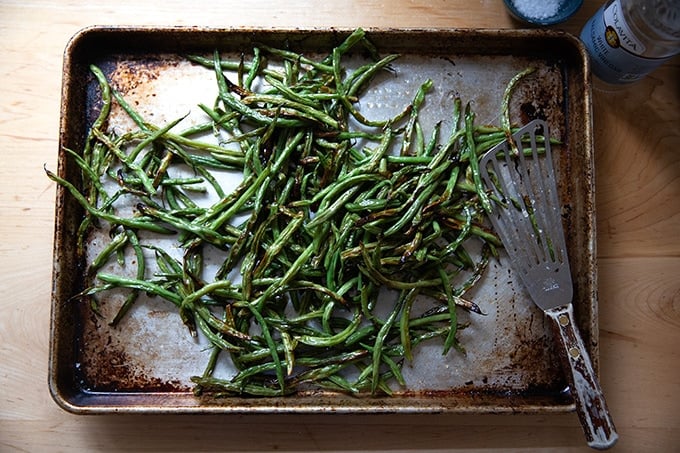 Roasted green beans on a skillet tossed with vinegar.