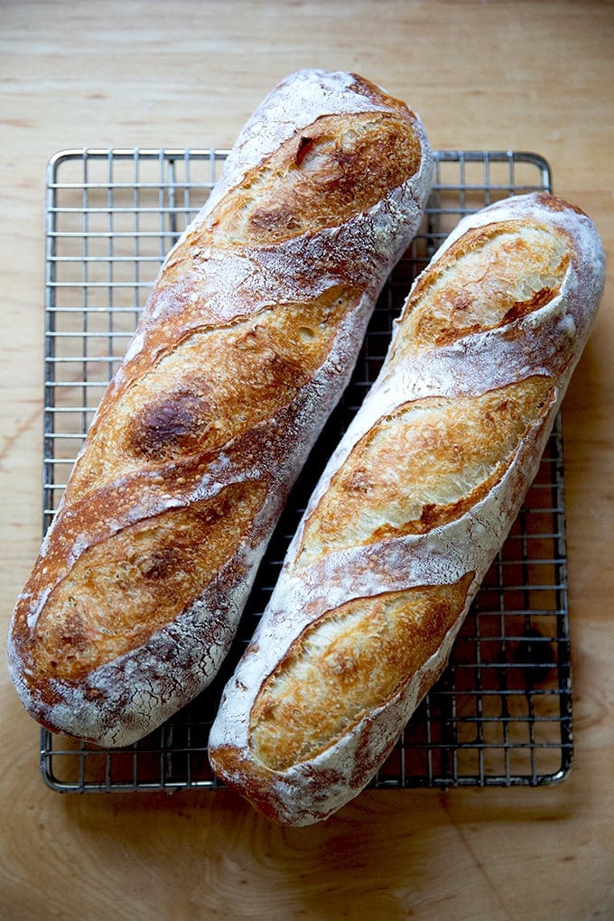 Two baked baguettes on a cooling rack.