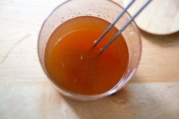 Iced tea in a large glass vessel with a ladle inside.