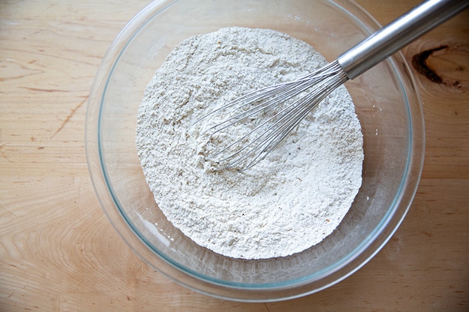 A bowl of whisked flour, salt, yeast, and caraway seeds.