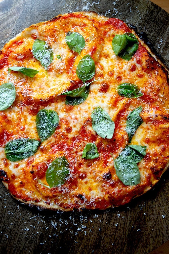 A just-baked, gluten-free Margherita pizza on a cutting board.