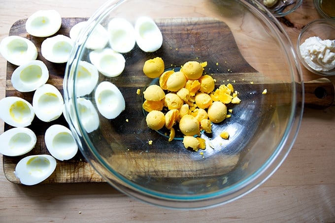 A bowl of hard-cooked egg yolks aside halved hard-cooked whites.