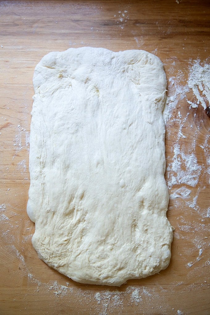 Sourdough discard toasting bread dough stretched out on a work surface into a large rectangle.