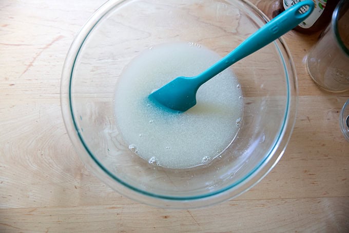 A large bowl holding water, salt, honey, and yeast, all stirred together.