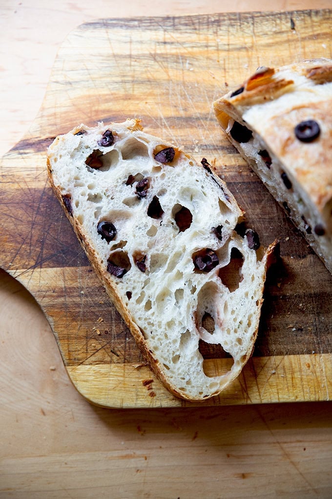 A slice of rosemary-olive sourdough on a cutting board. - 53
