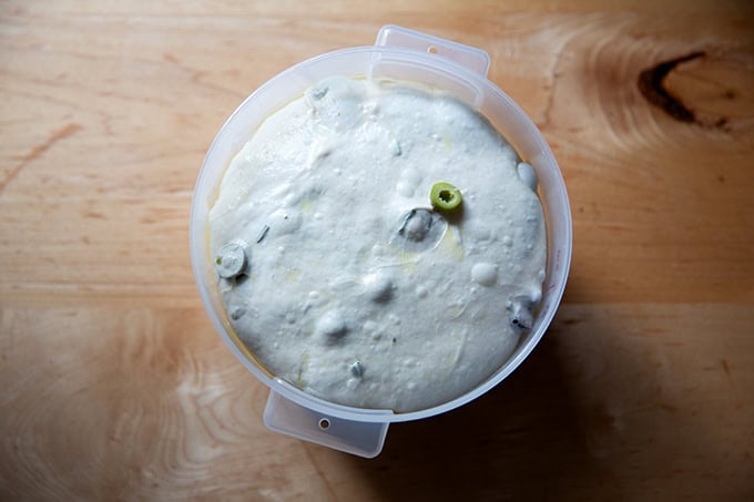 A 2-quart dough storage container filled with rosemary-olive sourdough dough risen nearly to the top. - 38