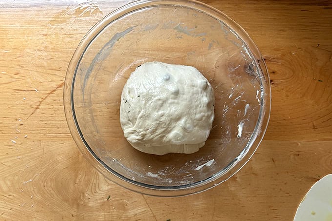 Rosemary olive sourdough dough folded and in a large glass bowl. - 34