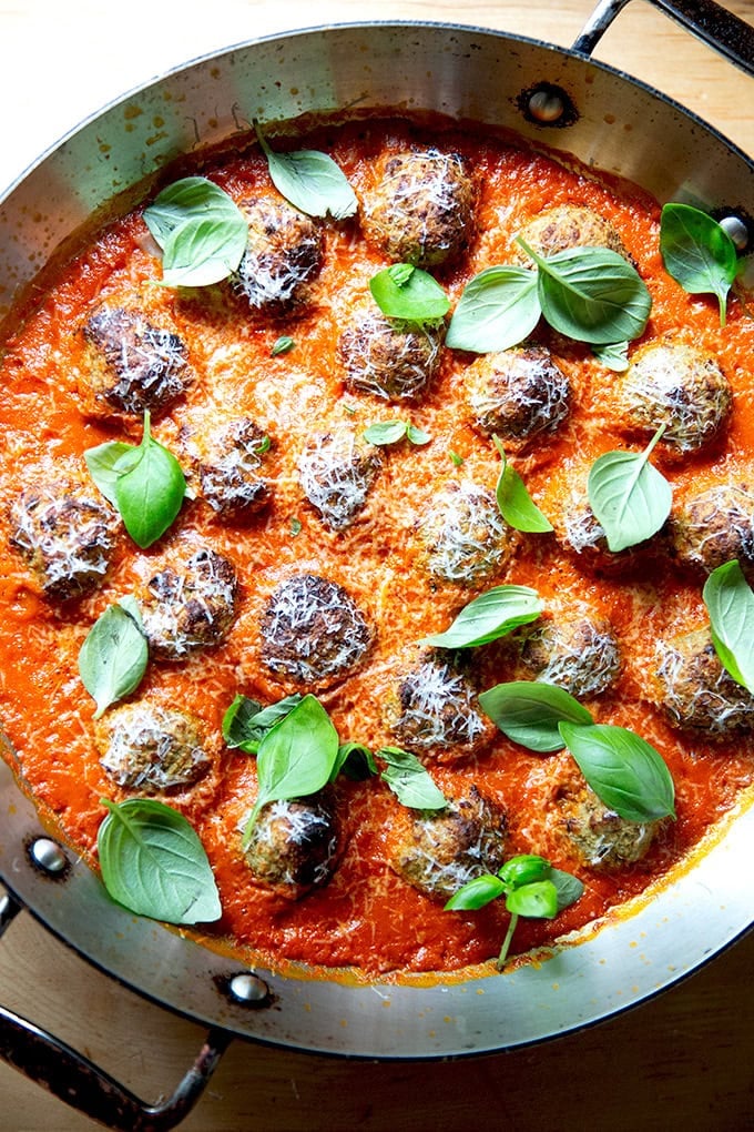 A skillet filled with tomato sauce, eggplant meatballs and fresh basil. - 15