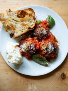 A plate of eggplant meatballs aside bread and ricottta.