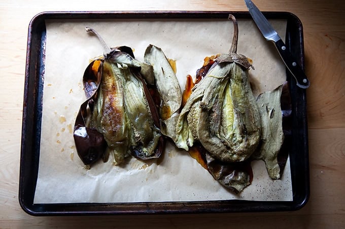 Roasted eggplant on a sheet pan, their skin split open to reveal their flesh. - 4