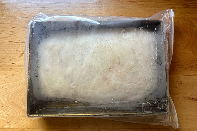A 9x13-inch pan filled with cinnamon-sugar focaccia, tucked inside a 2-gallon ziptop bag. - 41