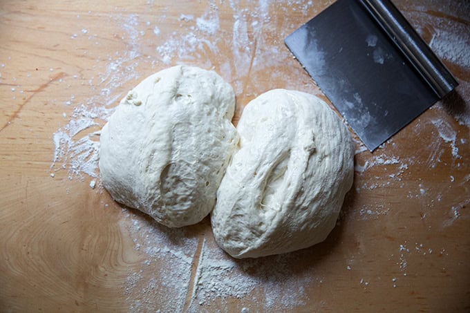 Grandma-style pizza dough, split into two portions, on a countertop.