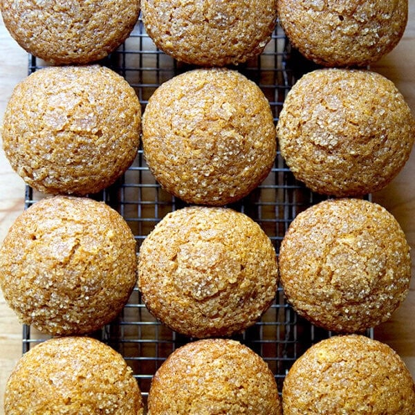 Twelve just-baked pumpkin muffins on a cooling rack.