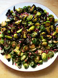 A platter of roasted Brussels sprouts tossed with pomegranate butter and pomegranate arils.