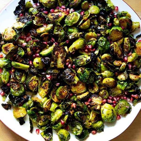 A platter of roasted Brussels sprouts tossed with pomegranate butter and pomegranate arils.
