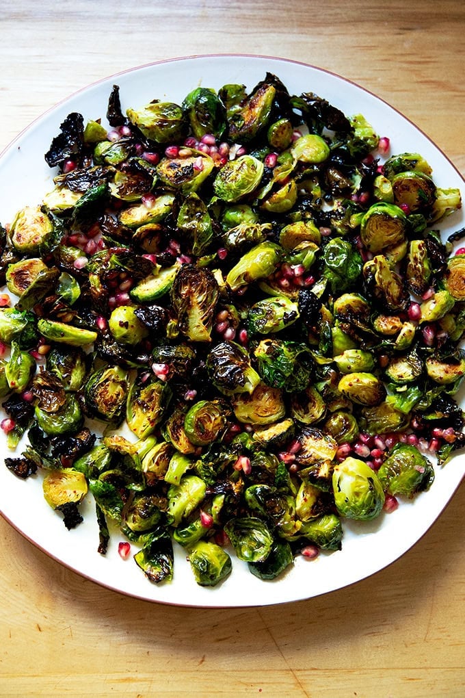 A platter of roasted Brussels sprouts tossed with pomegranate butter and pomegranate arils.