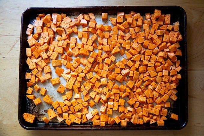 A sheet pan filled with cubes of sweet potatoes tossed with melted coconut oil, salt, and Aleppo pepper. - 33