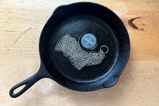 A cast iron skilled filled with a Cast Iron Chris chain cleaner and seasoning wax.