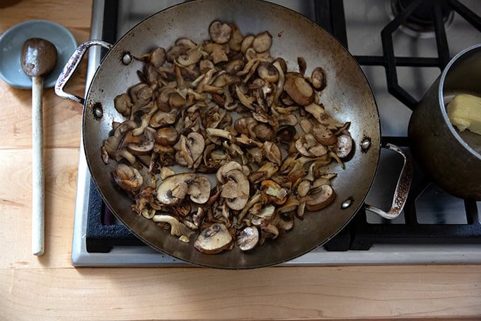 A large pan on the stovetop filled with sautéed mushrooms. - 41