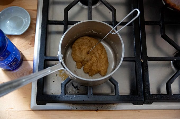 A roux in a small saucepan on the stovetop with Sherry added all whisked together. - 48