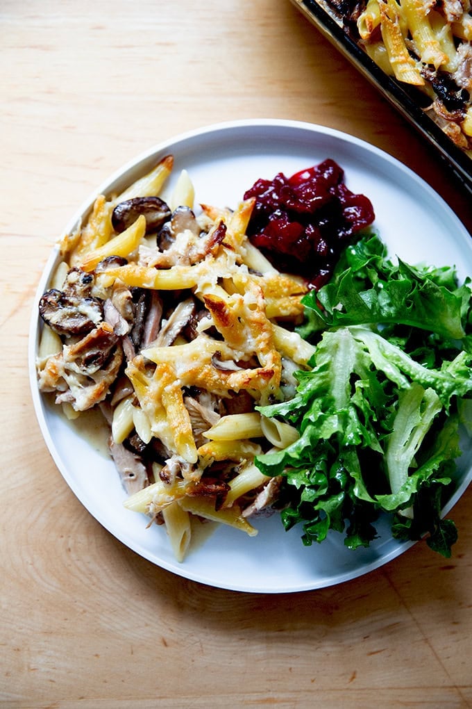 A plate of Turkey Tetrazzini aside salad and cranberry sauce.
