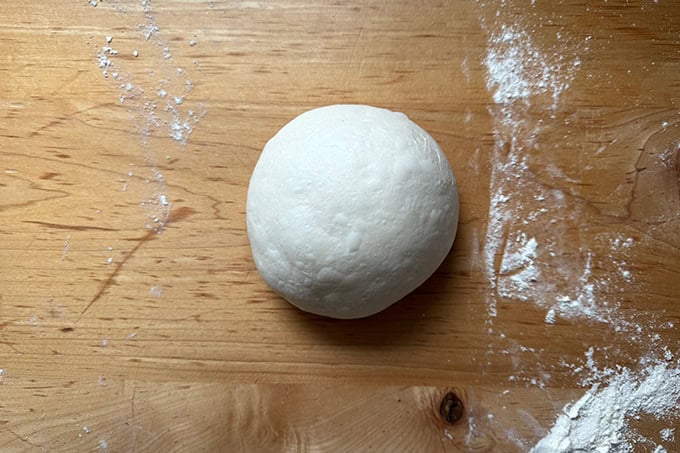 Giant sandwich roll dough, balled up on a countertop.