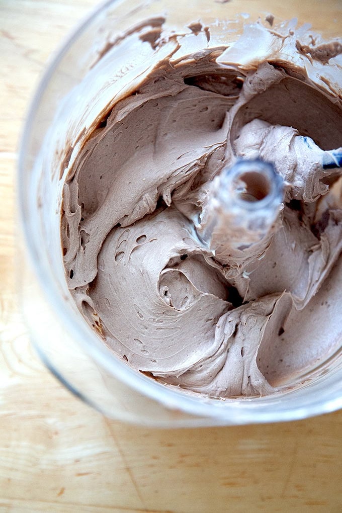 A stand mixer holding chocolate whipped cream cheese frosting.