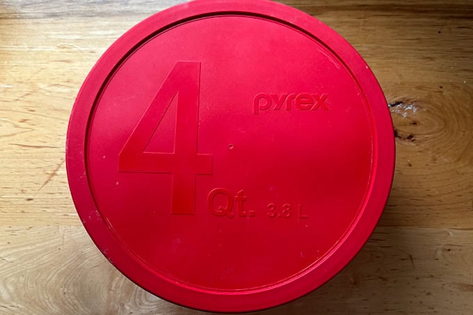 A lidded 4-qt Pyrex bowl holding sandwich roll dough.