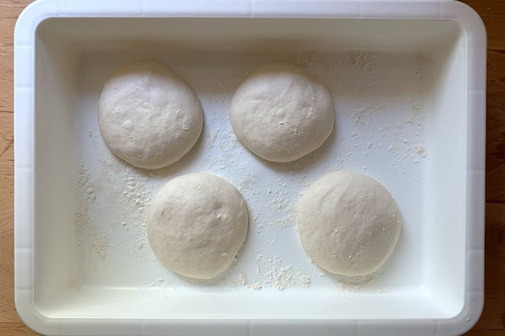 Four balled up portions of Overnight Sandwich Roll dough fully proofed in a DoughMate.