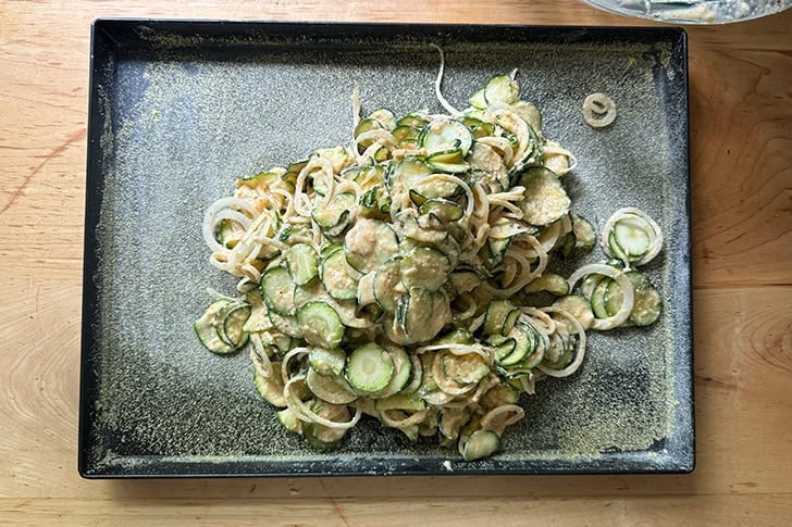 The zucchini-onion batter for scarpaccia poured into a buttered and cornmeal-lined sheet pan.