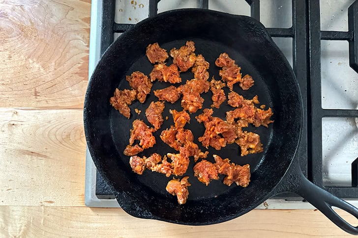 A cast iron skillet with chorizo browning in it.