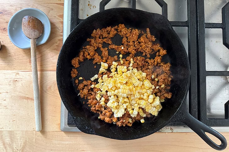 A cast iron skilled holding browned chorizo and corn.