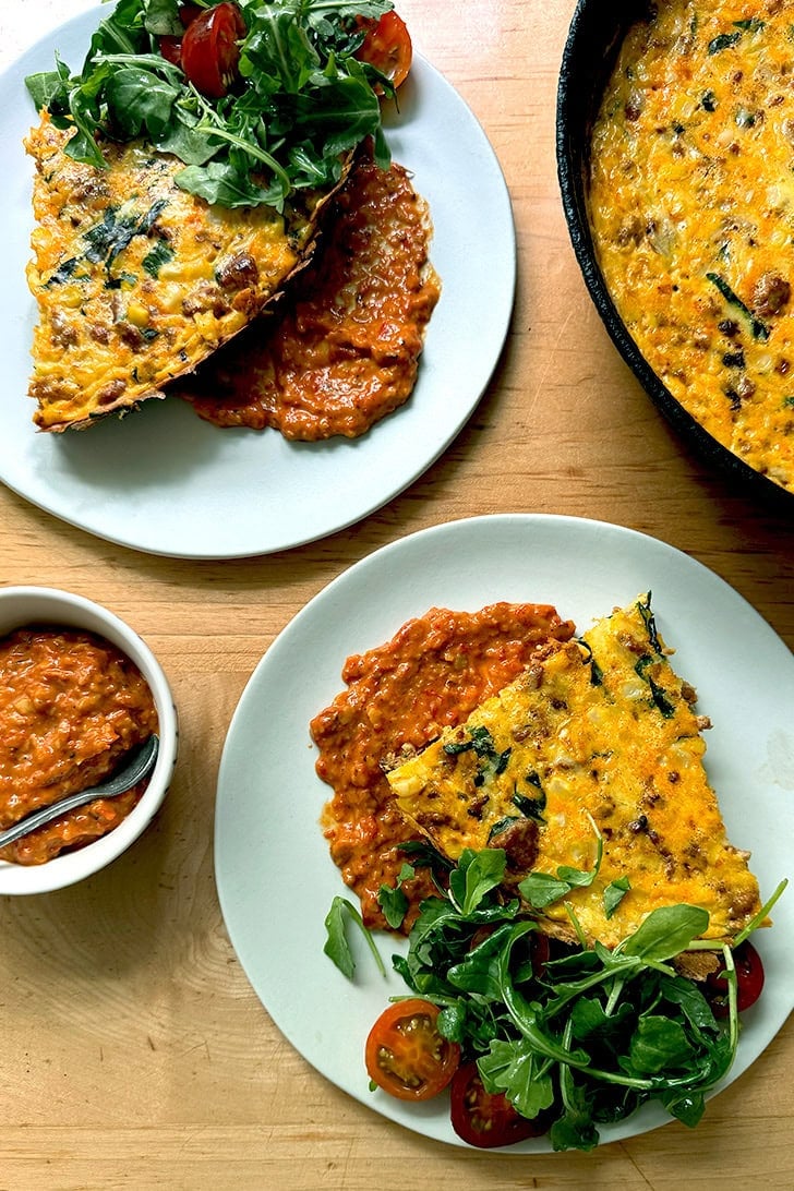 Two plates of chorizo and corn frittata atop a smear of homemade romesco.