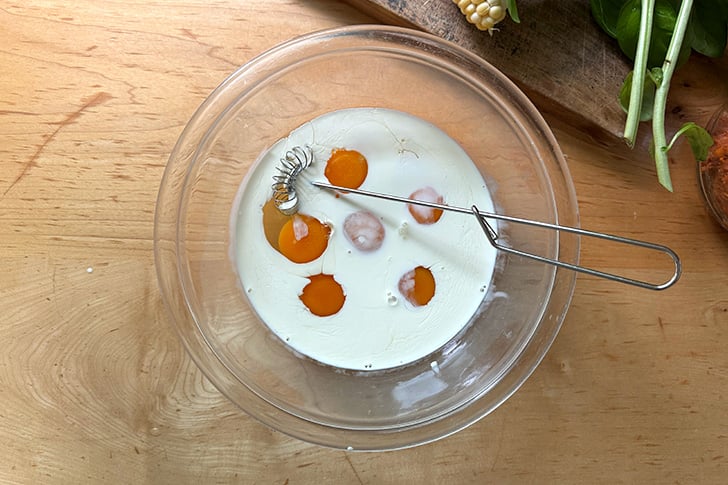 A bowl holding 6 eggs and 1/4 cup of heavy cream.