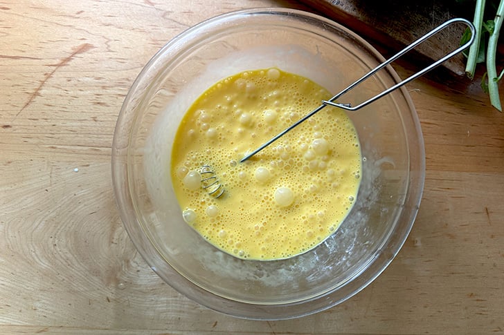 A bowl of whisked eggs, heavy cream, and salt.