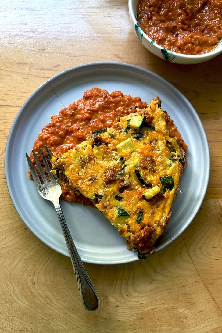 A plate of frittata atop a smear of homemade romesco.